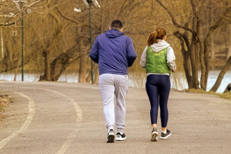 The photograph illustrates a male and female engaged in jogging as they traverse a road situated in a park