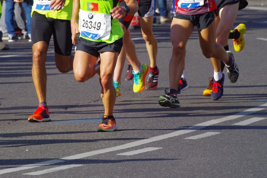 The photograph depicts the leg of an athlete in motion, actively competing in a marathon and advancing towards the viewer