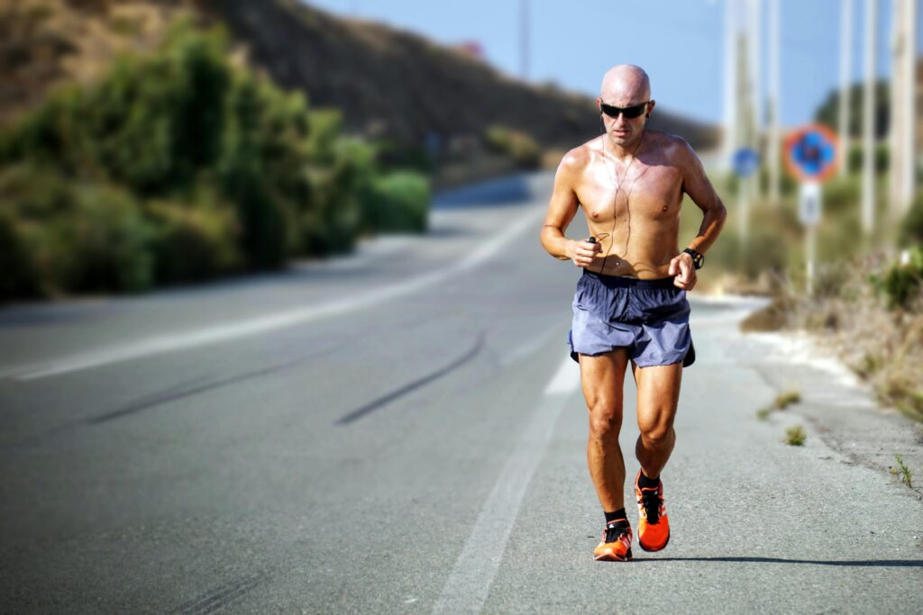 The image depicts an experienced runner approaching the camera, dressed in blue shorts, suggesting that it is a particularly warm day.